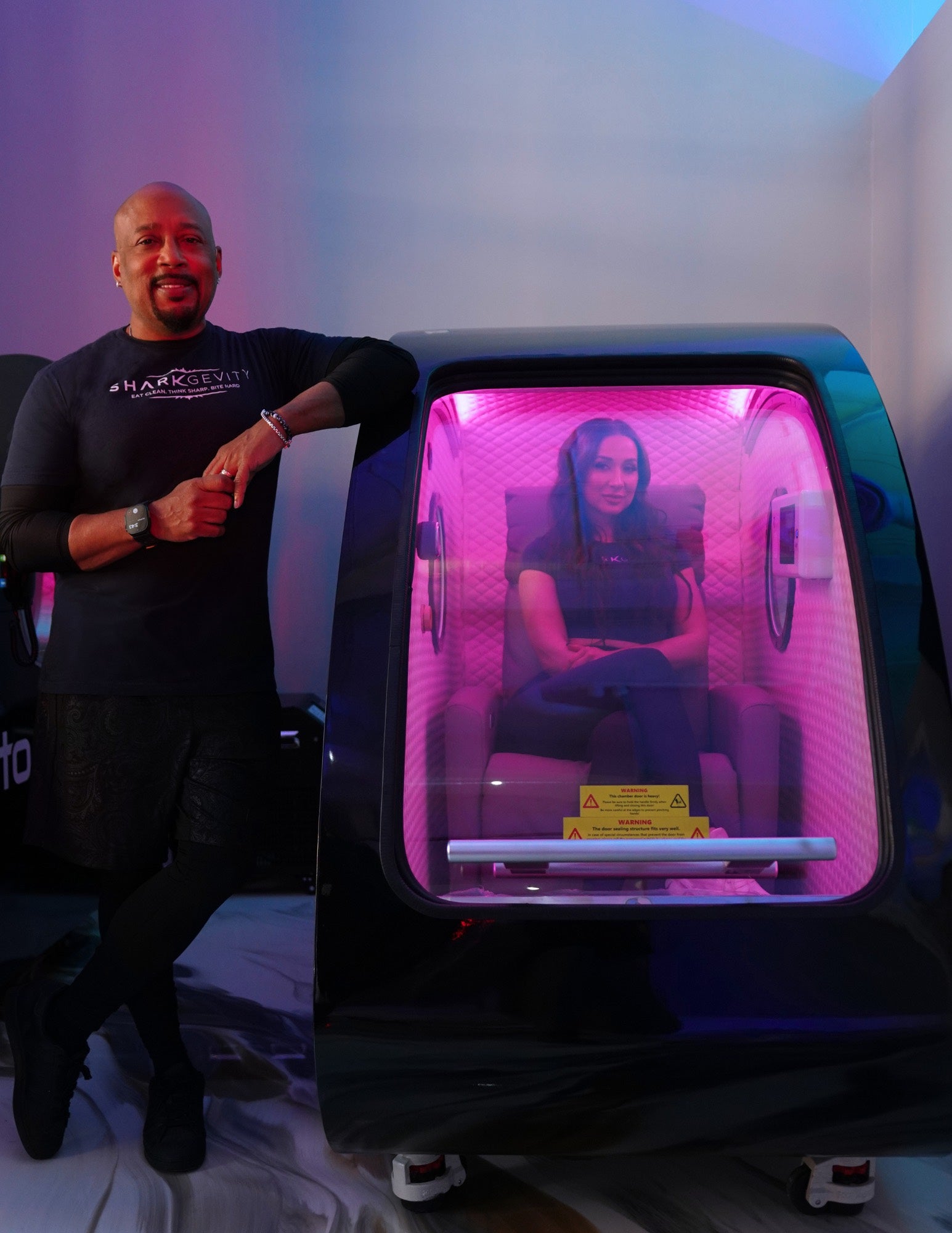 Two people with a Protocol⁴ wellness chamber, one seated inside